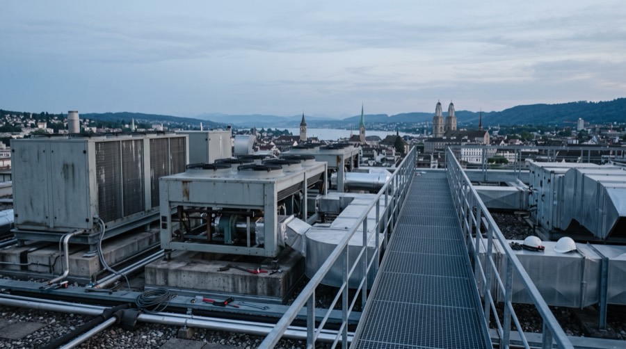 Lüftungs- und Kälteanlagen auf einem Flachdach in Zürich in der Abenddämmerung, im Hintergrund Stadt und See